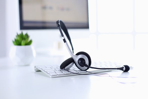 axvoice voip service review white office white desk and laptop keyboard with headset over  it monitor in the background